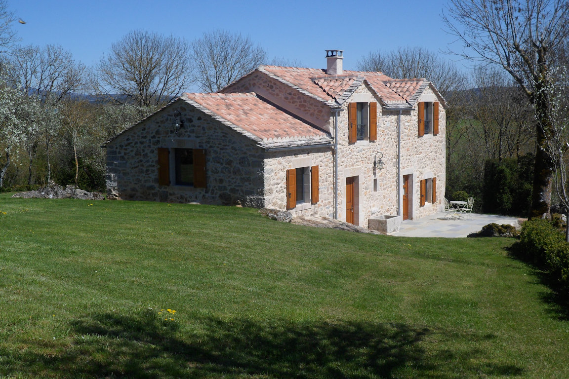 Stone façade of Le Rouge Gorge gîte, surrounded by lawn, near Sainte-Eulalie-de-Cernon