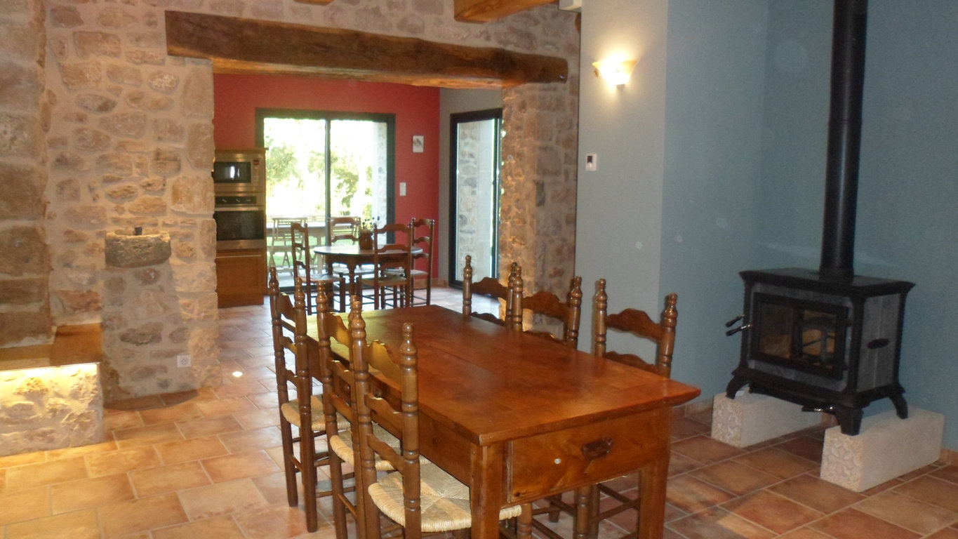 Open-plan living room and kitchen at Le Rouge Gorge gîte with wood-burning stove
